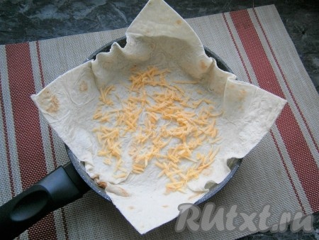 Из одного листа лаваша вырезать квадрат по диаметру сковороды так, чтобы лист лаваша закрывал и бортики внутри (как на фото). Твёрдый сыр натереть на средней тёрке. Дно сковороды, застеленной лавашом, посыпать небольшим количеством натёртого твёрдого сыра.