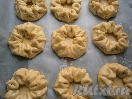 Противень застелить пергаментом и выложить все подготовленные заготовки булочек на достаточном расстоянии друг от друга, смазать их желтком, смешанным с 2 чайными ложками воды.

