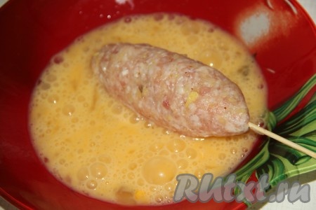 Два сырых яйца вбить в отдельную миску, размешать вилкой до однородного состояния и обмакнуть котлетки со всех сторон, держа за шпажки, в получившийся яичный кляр.
