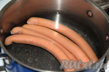 Сосиски положить в кастрюлю, залить водой и довести до кипения. Проварить 1-2 минуты и снять с огня.
