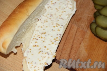 Булочку для хот-дога разрезать вдоль и смазать нижнюю часть соусом из майонеза и горчицы.
