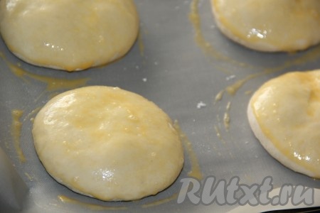 Булочки поднимутся. Яйцо взбить вилкой в небольшой ёмкости до однородности. Смазать верх булочек взбитым яйцом.
