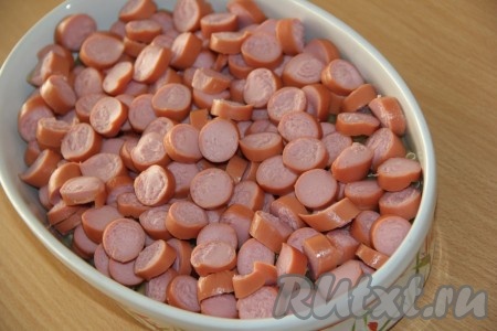 Сосиски нарезать на кружочки и выложить поверх макарон.