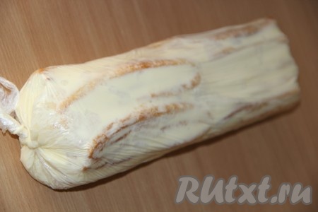 Плотно завернуть полоски теста с кремом в пищевую плёнку, сформировав полено. Концы пищевой плёнки замотать.