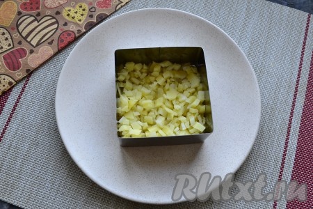 Варёную картошку нарезать маленькими кубиками, выложить первым слоем на тарелку (я формировала салат с помощью формочки) посолить и смазать майонезом.
