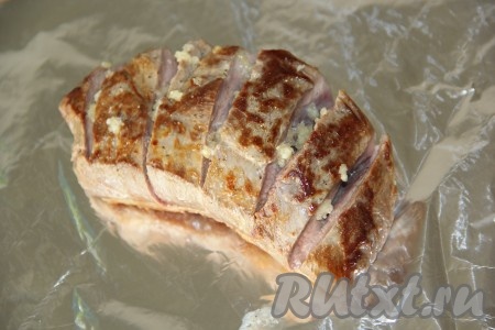 Переложить грудку на кусок фольги кожей вниз. Чеснок почистить и пропустить через пресс. Выложить чеснок в разрезы.
