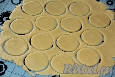Раскатать тесто на силиконовом коврике (или на столе, припылённом мукой) в пласт толщиной 0,5 сантиметра. Вырезать рюмкой кружочки.