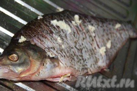 Посолить рыбу по вкусу, втирая соль. Чеснок почистить и пропустить через пресс. Натереть леща чесноком снаружи.