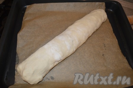 Начиная с длинного края, сверните тесто с начинкой в рулет. Потом подверните концы рулета и защипните тесто руками (это нужно для того, чтобы начинка не начала вытекать в процессе выпечки). Противень застелите пергаментом для выпечки. Лучше всего использовать силиконизированную бумагу для выпечки - она более качественная и к ней выпечка не пристаёт. Если не уверены в качестве пергамента, то можно его дополнительно смазать растительным маслом. Выложите рулет на пергамент так, чтобы шов рулета оказался внизу.
