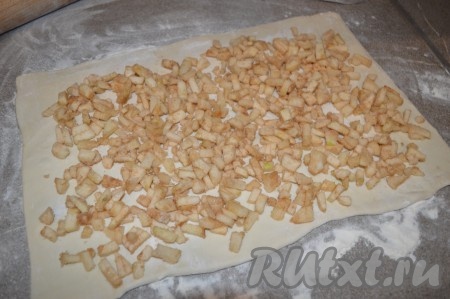 Выложите начинку из яблок на раскатанное слоёное тесто, немного отступив от краёв.
