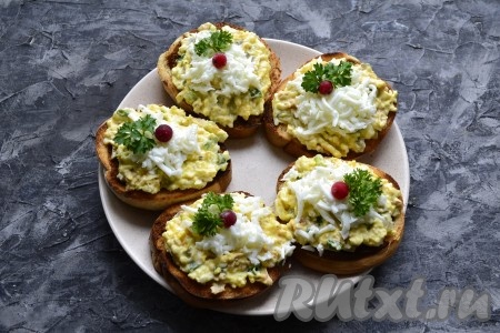 Оставшимися натёртыми белками (1/3 часть белков, которые мы откладывали) посыпать бутерброды сверху и украсить их веточками петрушки и ягодами красной смородины (можно заменить на зёрна граната).
