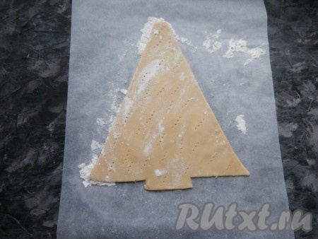 Острым ножом вырезать фигуру ёлки по шаблону. Излишки теста убрать (использовать для формирования остальных 2-х коржей). Шаблон также убрать, а тесто по всей поверхности наколоть вилкой.
