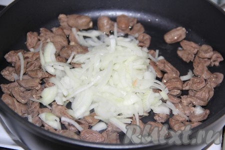 По прошествии 20 минут добавить к куриным сердечкам лук и обжарить на среднем огне, помешивая, в течение 3 минут.
