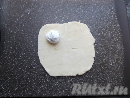 Каждый шарик теста на поверхности, присыпанной мукой, раскатать в тонкую лепёшку, визуально разделить её на 4 части. В верхнюю левую часть разместить 1 чайную ложку взбитых белков.