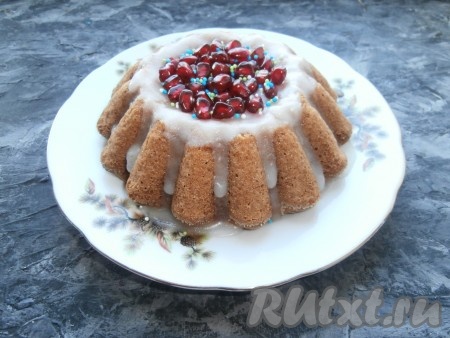 Дать кексу немного остыть и аккуратно перевернуть его на тарелку, полностью дать остыть. Для приготовления глазури в сахарную пудру постепенно добавлять лимонный сок с водой, тщательно перемешивая, до однородности и получения нужной консистенции. Полить остывший кекс глазурью и украсить (я украсила зёрнами граната и кондитерской посыпкой).