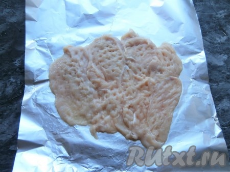 Куриное филе нарезать тонкими пластами, как для отбивных. Отбить мясо молоточком. Отбитые кусочки филе выложить на лист фольги внахлёст - одним тонким слоем.
