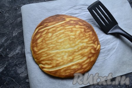 Затем достать корж из духовки, дать немного остыть на пергаменте (в течение 2-3 минут) и корж отлично снимется с пергамента с помощью лопатки. Снизу корж красиво зарумянивается. Остудить полностью. Аналогично, выкладывая и размазывая по 4-5 столовых ложек теста по нарисованному кругу, испечь все коржи и полностью их остудить.
