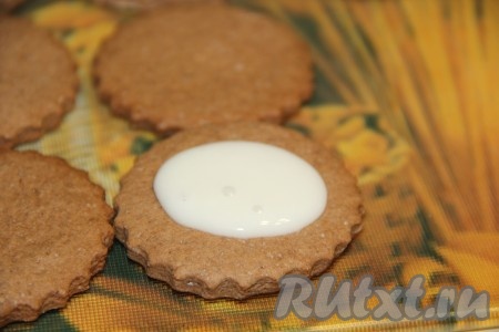 На середину каждого шоколадного печенья выложить 1/2 чайной ложки глазури.
