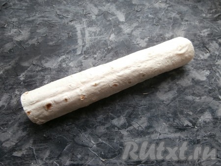 Лаваш плотно свернуть в рулет, начиная с края со шпротами. Обернуть рулет пищевой плёнкой и отправить на 1 час в холодильник.
