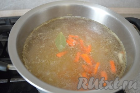 Поставить бульон снова на огонь, довести до кипения, опустить в него нарезанную морковку, лавровый лист и куриное мясо. Варить суп, примерно, 5 минут с момента закипания на среднем огне.
