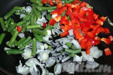 Лук нашинковать, перец нарезать кубиками и вместе с фасолью (можно использовать свежую или замороженную) обжарить на растительном масле.