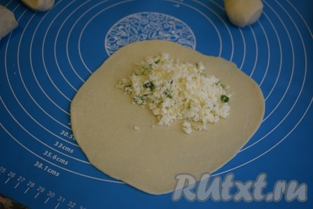 Далее на поверхности, припылённой мукой, каждый кусочек раскатываем в лепёшку толщиной около 1-2 мм. На один край каждой лепёшки выкладываем по 2 чайные ложки начинки.
