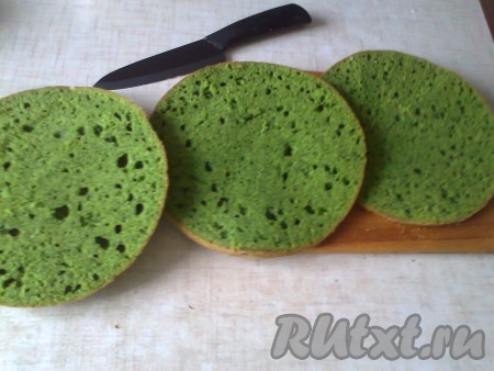 Немного крема надо оставить для украшения верха и боков торта. С бисквита срежьте верхушку, она понадобится для оформления тортика. А корж разделите на 2 части.
