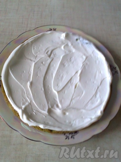 На блюдо выложите первый корж и промажьте его кремом.
