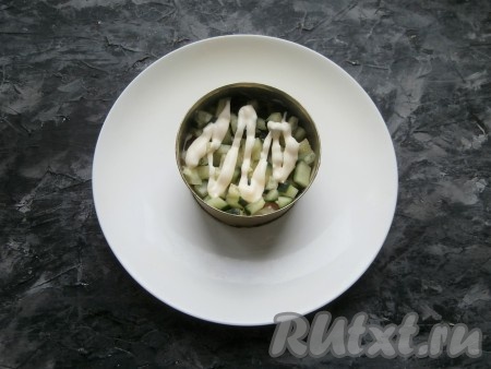 Рыбу немного смазать майонезом и далее выложить слой нарезанного кубиками свежего огурца, нанести майонез.
