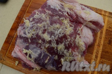 Затем обваляйте мясо в чесноке, натёртом на тёрке. Выложите кусок свинины в миску, накройте крышкой, уберите мясо в холодильник на 1-2 часа промариноваться и просолиться.
