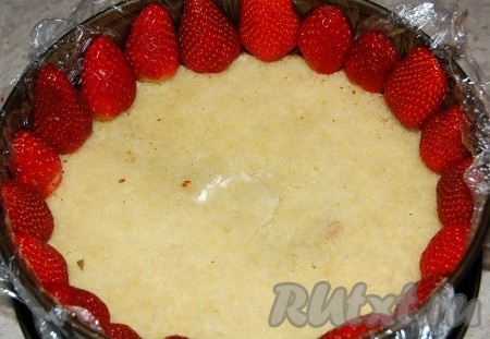 Часть клубники разрезать пополам и выложить по окружности формы срезом к бортику.