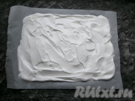 Противень застелить листом пергамента очень хорошего качества, выложить белковую массу, размазать её в виде прямоугольника толщиной около 1 см. Размер коржа у меня получился 27 см х 24 см.