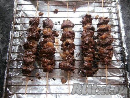 Готовить шашлык при температуре 200-220 градусов до румяности сверху, после чего шпажки перевернуть и также дать мясу зарумяниться с другой стороны. По времени жарка займёт минут 20-25 (смотрите по своей духовке). Когда сало (или жир) на фольге начнёт дымиться и гореть, шашлык готов!
