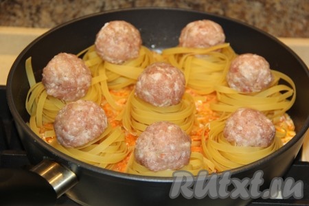 На сковороду поверх овощей выложить макаронные гнёзда, а в середину каждого гнездышка поместить по одной фрикадельке из фарша.