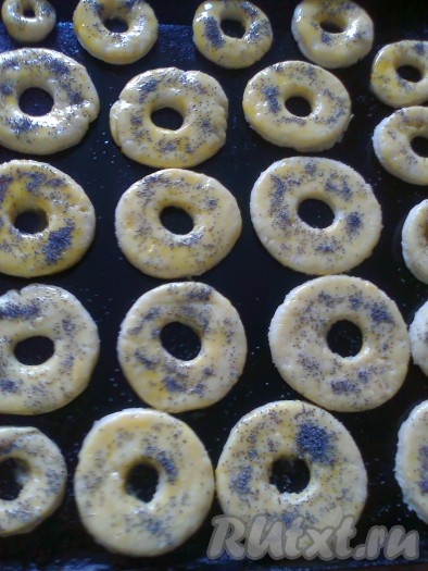 Заготовки переносим на противень, смазанный растительным маслом (или на промасленный пергамент). Смазываем творожные бублики желтком и часть посыпаем маком,
