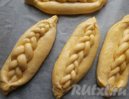 Все дрожжевые булочки с повидлом выложить на противень, застеленный пергаментом, прикрыть плёнкой и оставить на 20 минут. После этого смазать тесто желтком.
