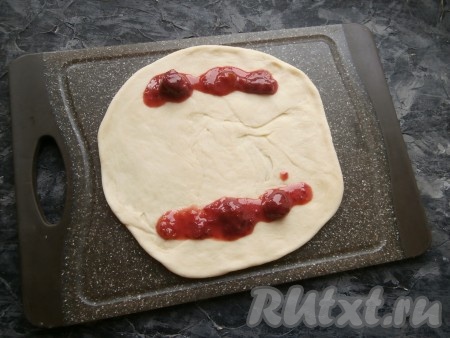 Каждую большую часть теста раскатать на припылённой мукой поверхности в лепёшку диаметром 20-21 см. Сверху и снизу лепёшек, ближе к краям, выложить варенье в виде полос.
