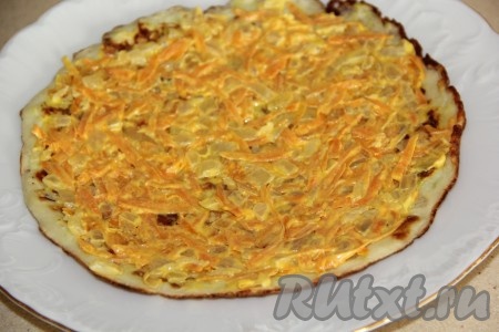 Теперь приступаем к сборке закусочного торта, для этого на плоскую тарелку нужно выложить кабачковый корж, смазать половиной морковно-луковой начинки.
