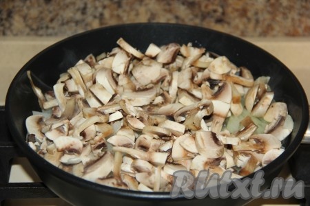Промыть свежие шампиньоны, нарезать на пластинки, затем выложить к обжаренному луку.
