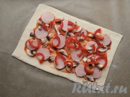 На смазанную часть теста выложить кружочки сардельки, сладкий перец и грибы.
