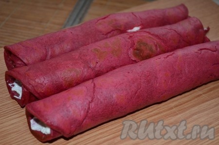 На каждый блин из свеклы намазываем творожную начинку, скручиваем трубочкой.