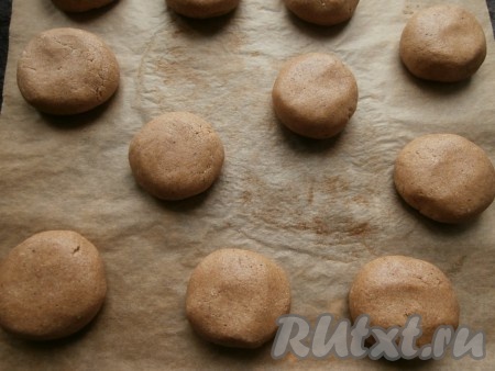 Тесто разделить на 10-11 частей и немного влажными руками скатать шарики, выложить их на противень, застеленный пергаментом, на расстоянии друг от друга около 5-6 см. Шарики немного придавить рукой.
