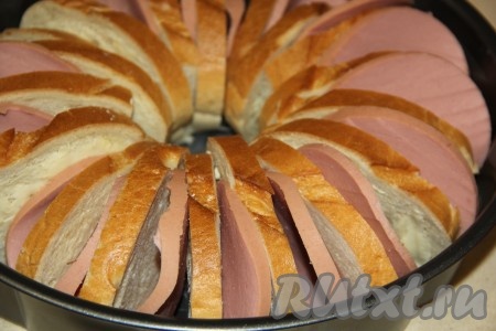 Кусочки батона расставить (поставить на бок) по кругу в форме. Между кусочками батона выложить колбаску.
