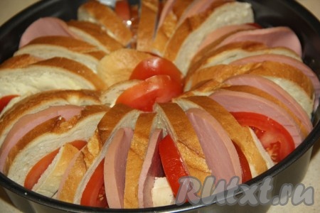 Затем между кусочками батона и колбасы выложить кружочки помидора. Чтобы ломтики батона "стояли" ровно, можно несколько кусочков батона подрезать, а затем вставить в серединку, чтобы заполнить пустоту. Если осталось масло, тогда, разделив его на небольшие кусочки, разместите их между кусочками колбасы и помидора.
