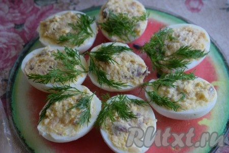 Далее выкладываем веточки укропа с одной стороны яиц, фаршированных скумбрией и желтками. Укроп, прикрепившись к начинке, будет хорошо держаться на поверхности.
