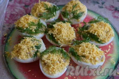 Затем, слегка отодвигая укроп, посыпаем наши фаршированные яйца натёртыми желтками. Расправляем веточки укропа и получаем закуску, похожую на веточки мимозы. Яйца, фаршированные скумбрией, готовы, остаётся только выложить их на блюдо для подачи и отправить в холодильник на 1-2 часа.
