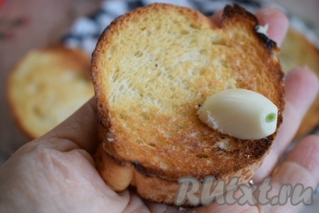 Обжаренный хлеб снимаем со сковороды, слегка остужаем. Два зубчика чеснока чистим и, обмакивая в соль, натираем поджаренные кусочки багета с двух сторон чесноком.