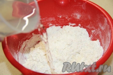 Влить холодную воду, перемешать вначале ложкой, а затем вымесить руками.
