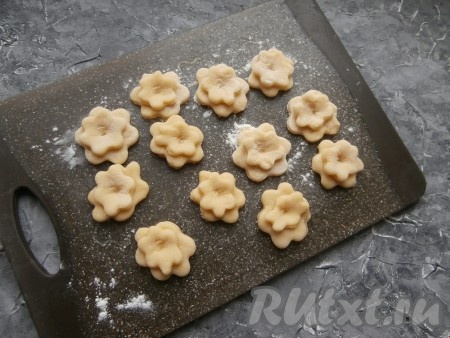 Количество больших и маленьких цветочков должно быть одинаковым. Центры больших цветов смазать сырым яичным белком. Меньшего размера цветочки прикрепить к большим цветам (благодаря белку, маленькие цветы будут хорошо держаться на больших) и придавить сверху пальцем.
