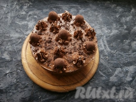 Шоколадный торт украсить оставленной частью крема из варёной сгущёнки и масла, выдавливая его из кондитерского мешка с насадкой "звездочка", а также трюфельными конфетами, рубленным чёрным шоколадом и кондитерской посыпкой. По желанию и, если есть в наличии, тортик можно немного украсить пищевым блеском. Дать торту пропитаться при комнатной температуре в течение 1 часа, а затем отправить его в холодильник часов на 5-6.